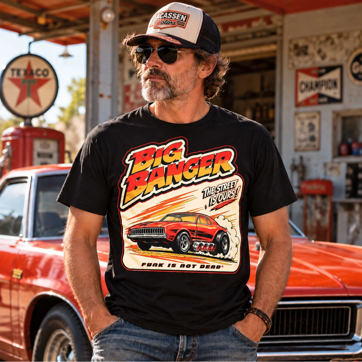 Homme portant le T-shirt Big Banger Funk Is Not Dead® dans un garage avec muscle car vintage